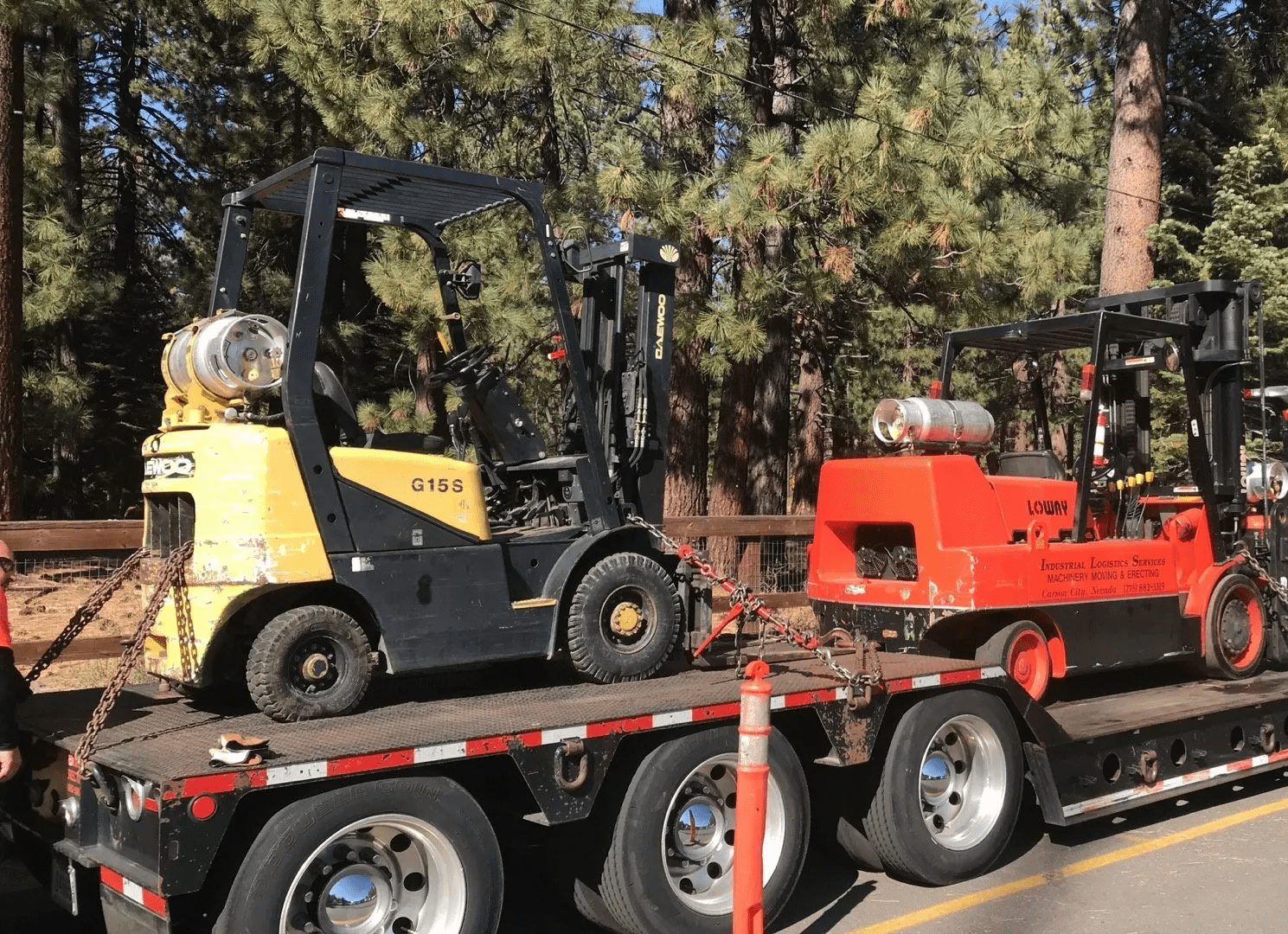 Truck and trailer hauling 2 large forklifts